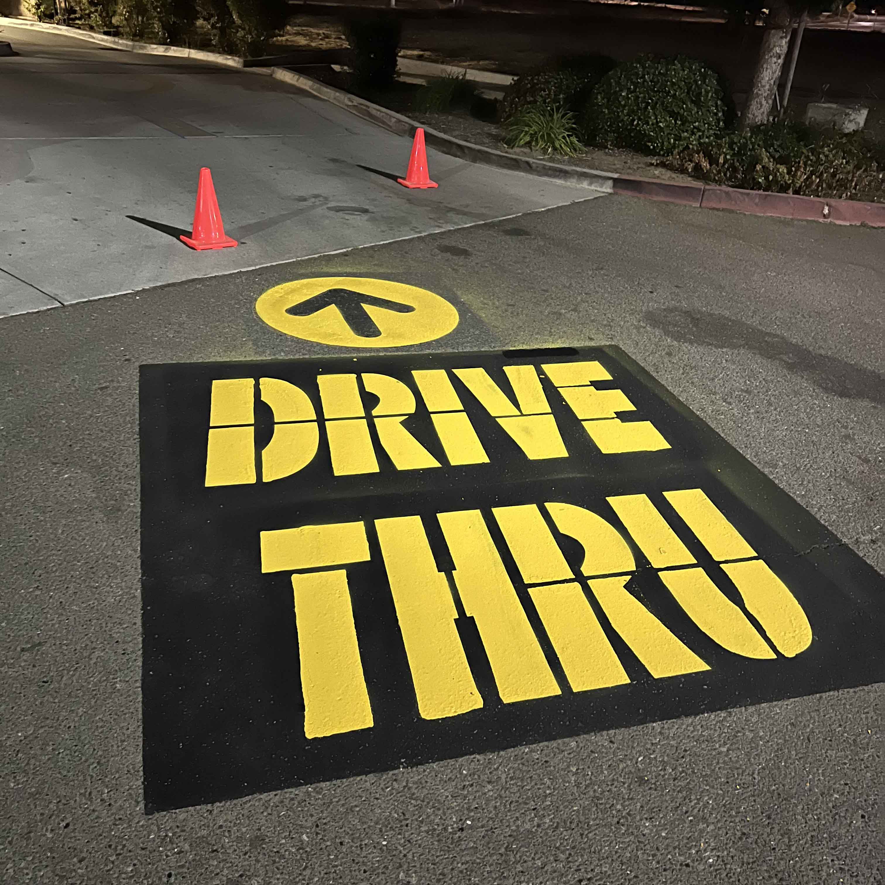 Yellow drive-through pavement marking on an asphalt parking area